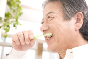 Senior men brush their teeth